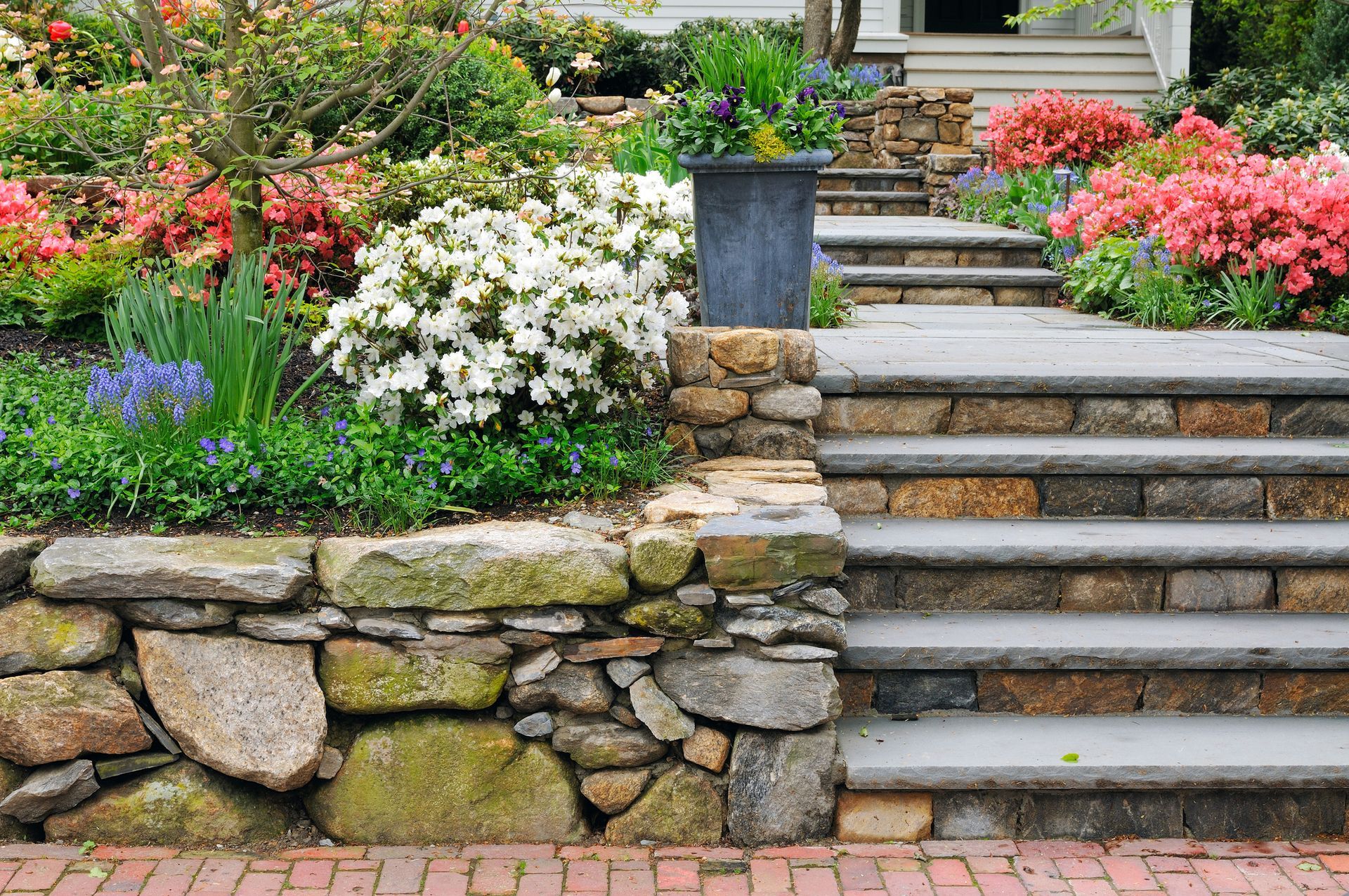 A stone wall surrounds a set of stairs leading up to a house.
