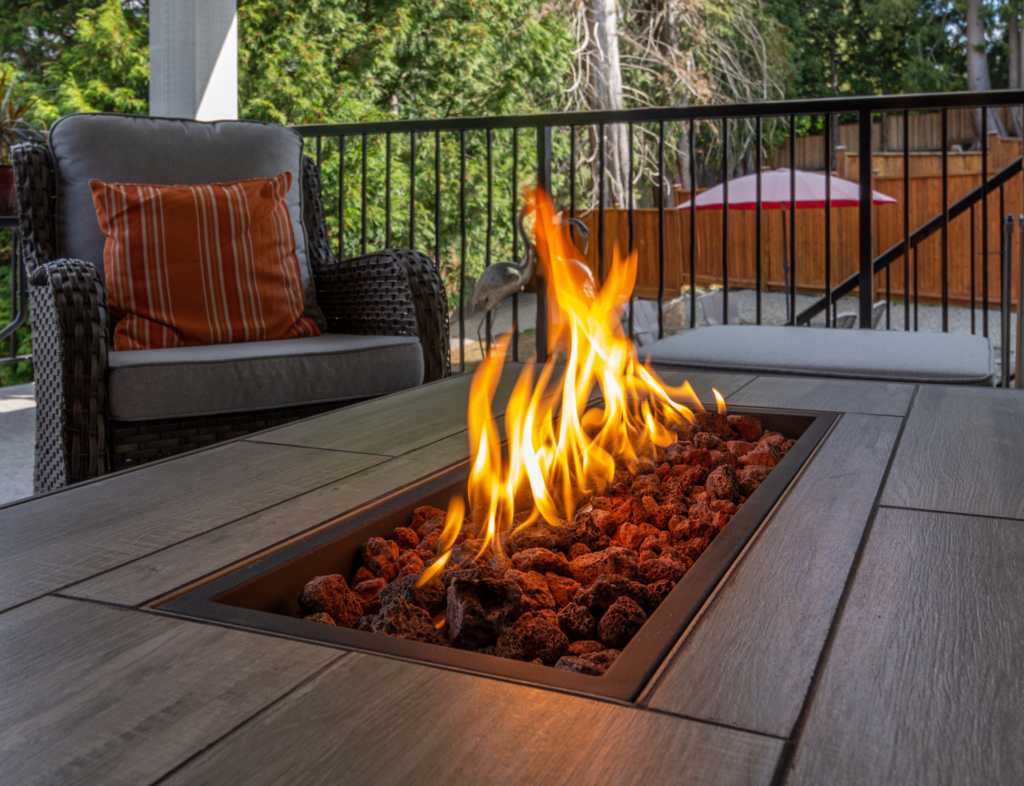 A fire pit is sitting on top of a wooden table on a patio.