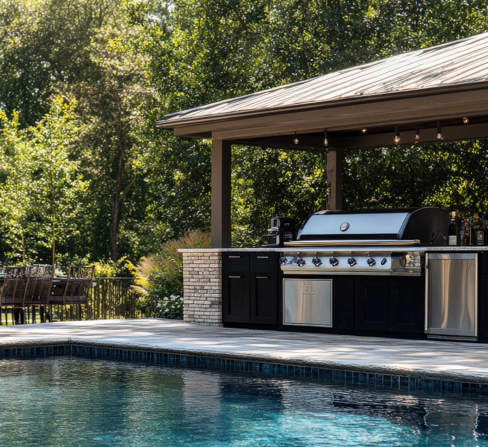 An outdoor kitchen with a grill next to a swimming pool.