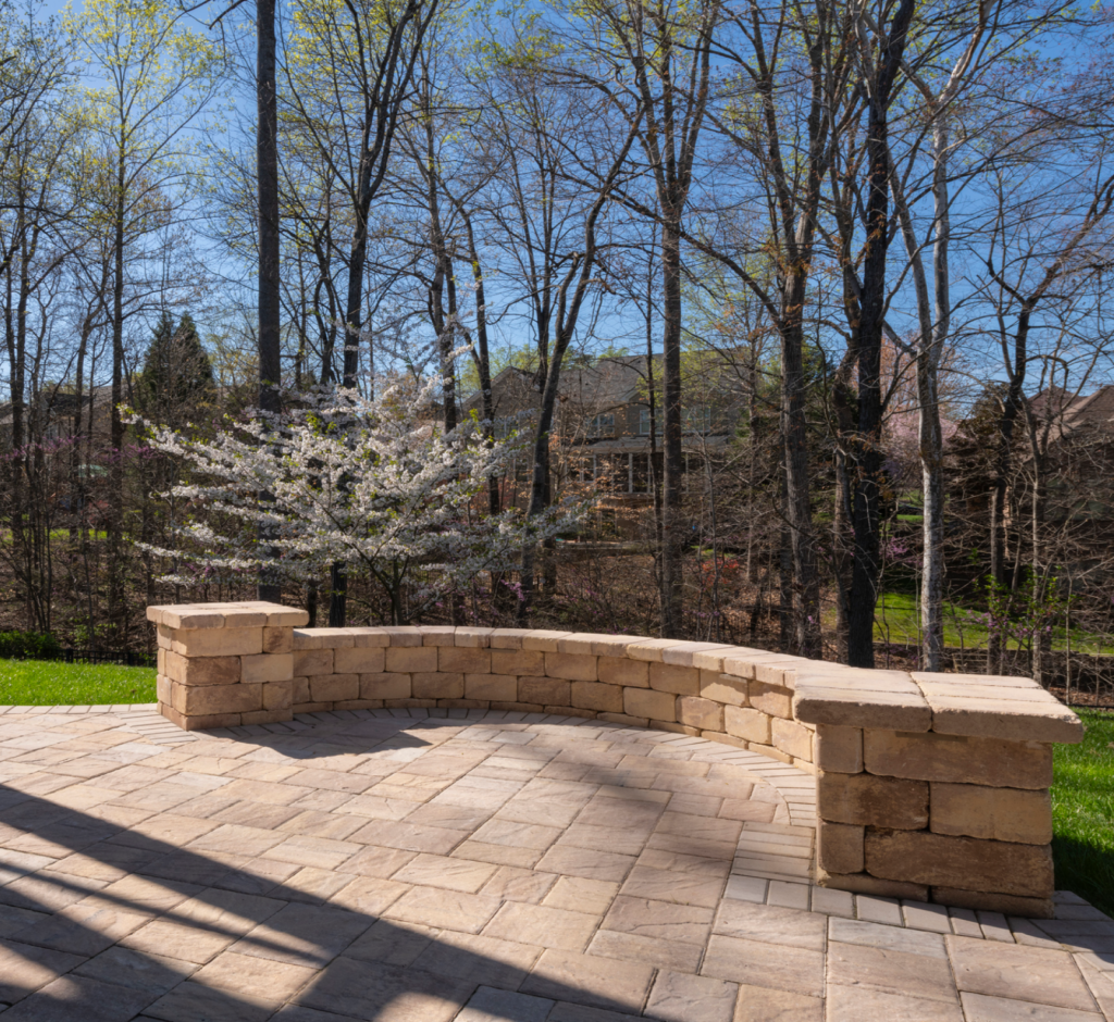 A curved stone bench on a patio with trees in the background
