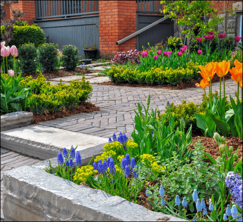 A brick walkway surrounded by flowers and shrubs