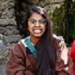 A woman with long hair and glasses is smiling for the camera.
