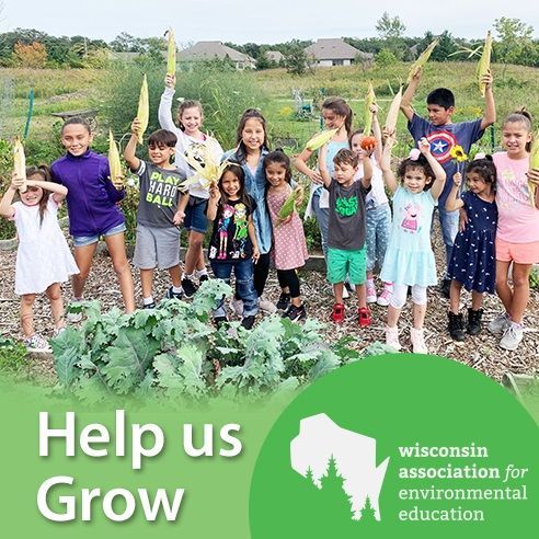 A group of children are standing in a garden holding corn on the cob.