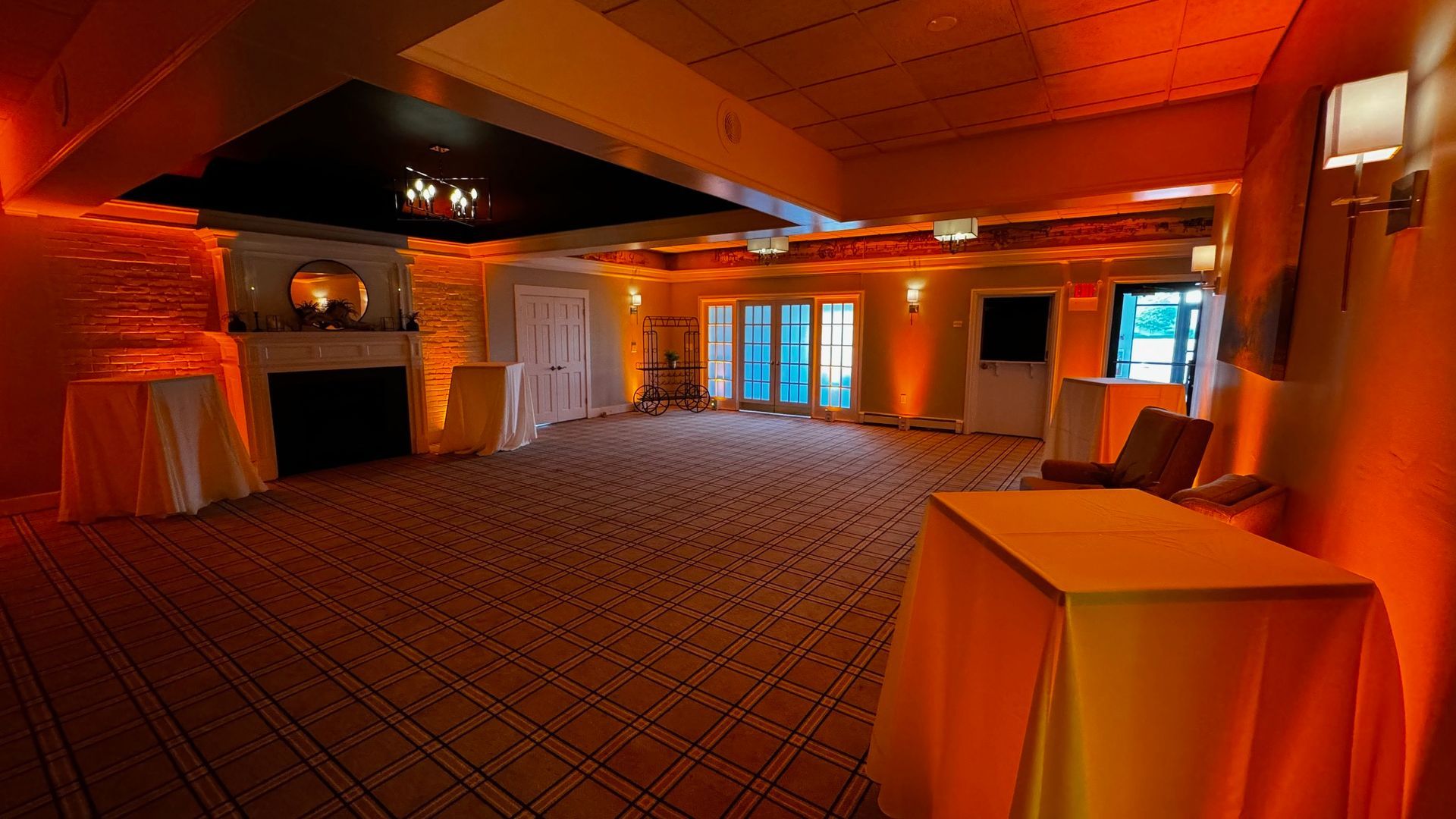 A large empty room with tables and chairs and a fireplace.