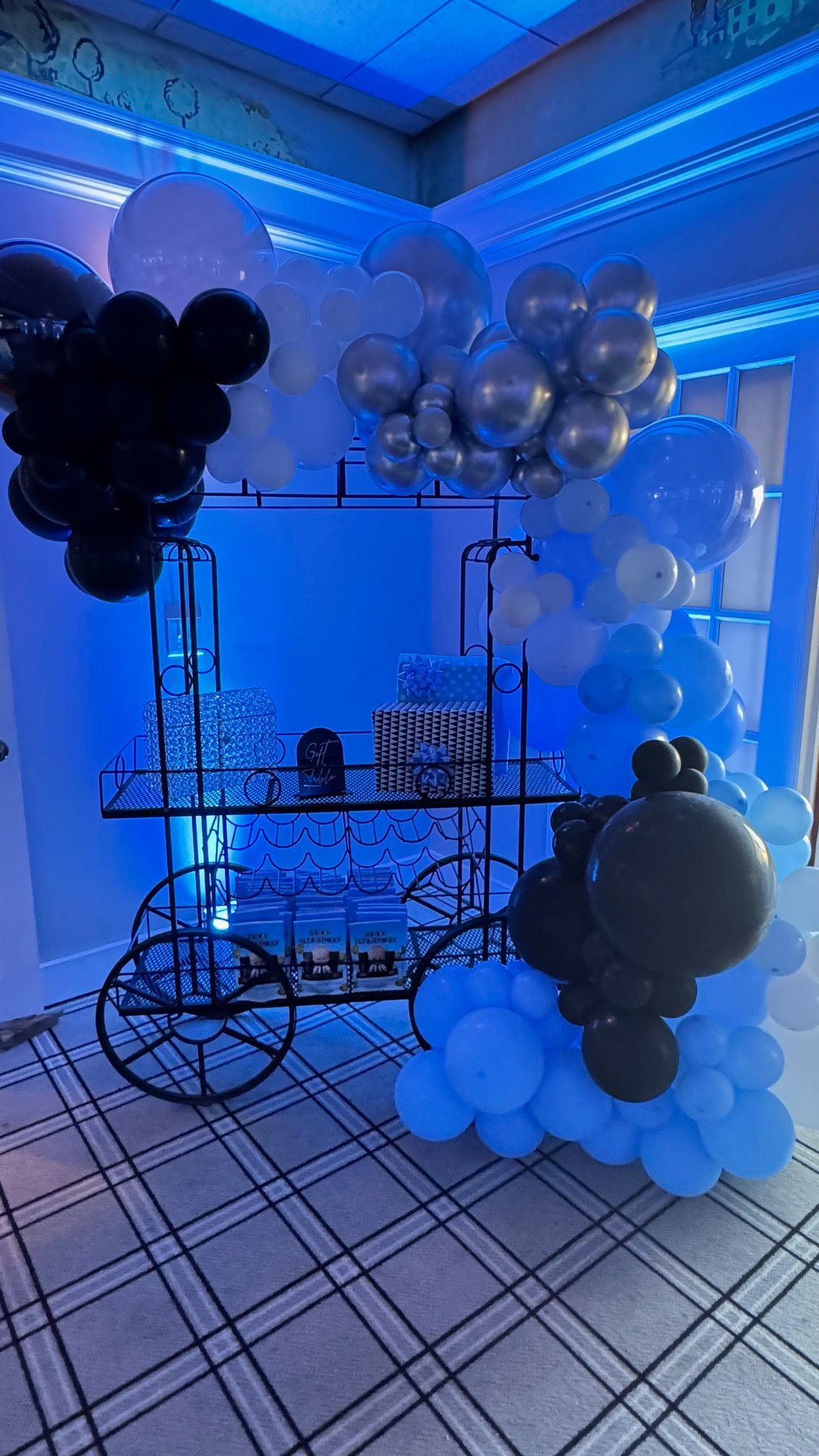 A cart filled with balloons is sitting in a room.