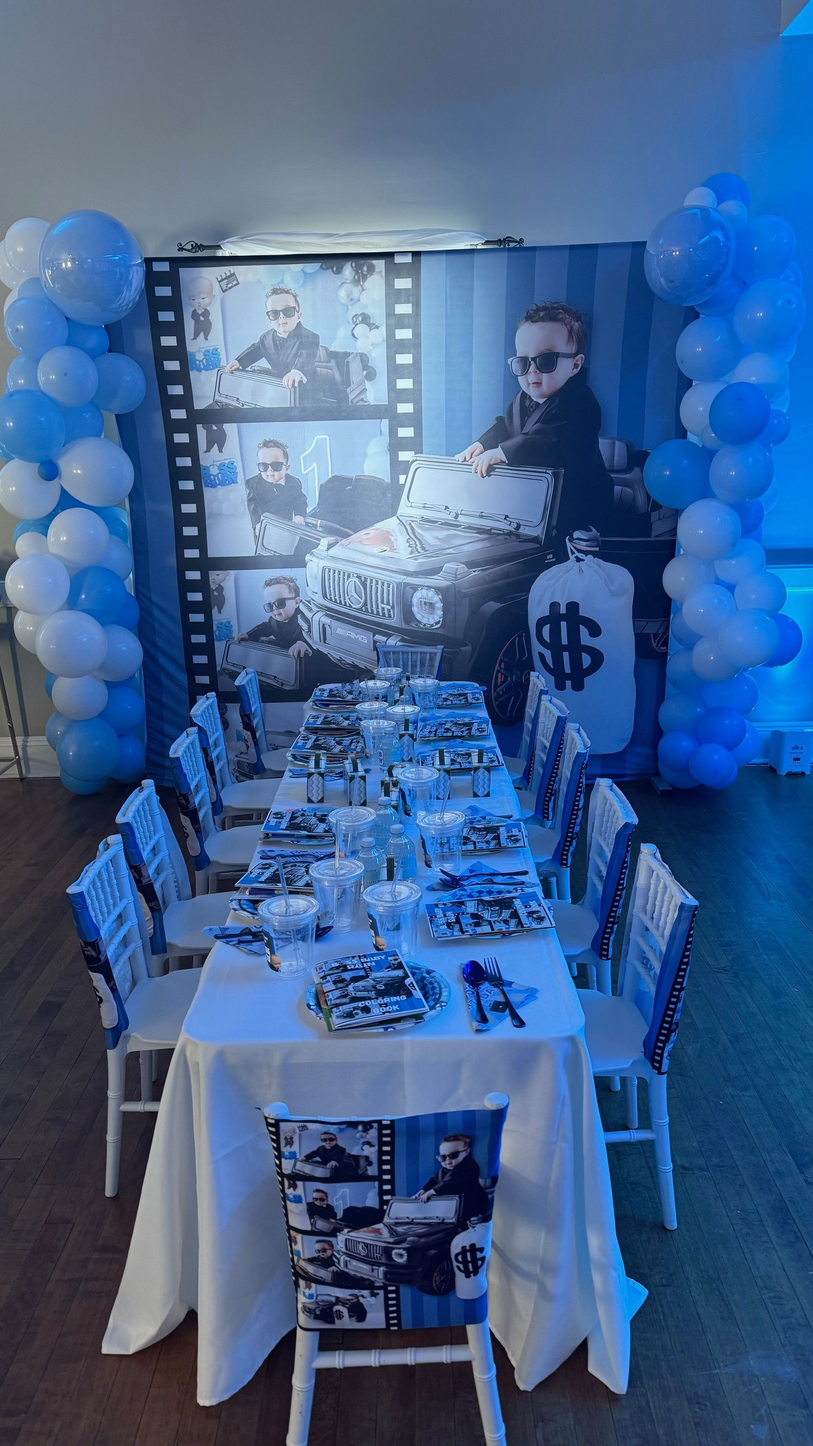 A long table with chairs and balloons in a room.
