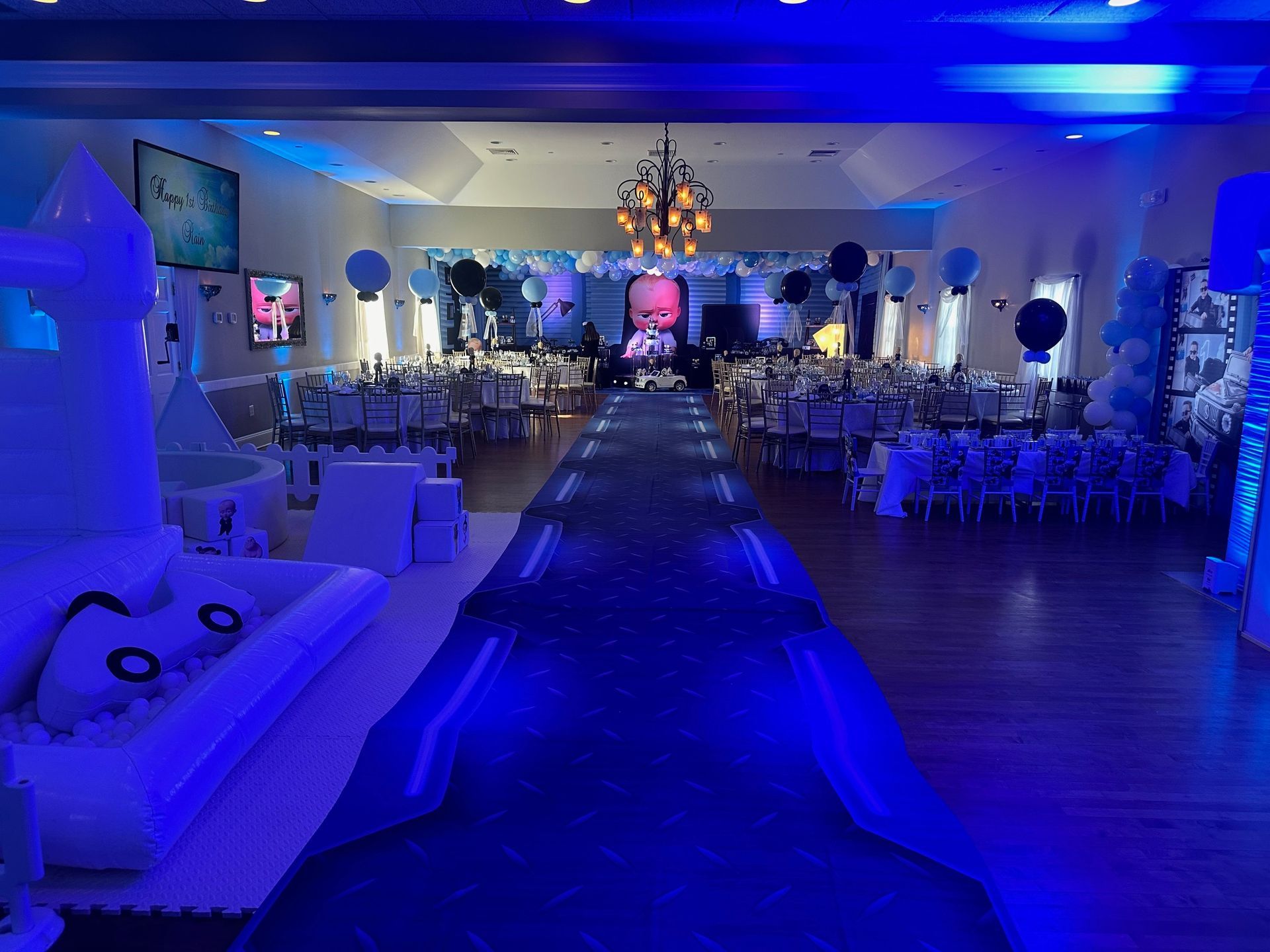 A long table with chairs and balloons in a room.