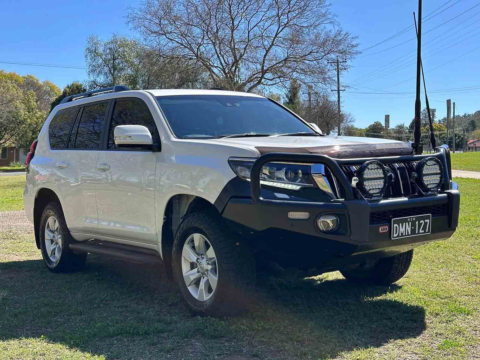 A White SUV With A Black Bumper Is Parked In A Grassy Field — Brody’s Car Detailing In Tamworth, NSW