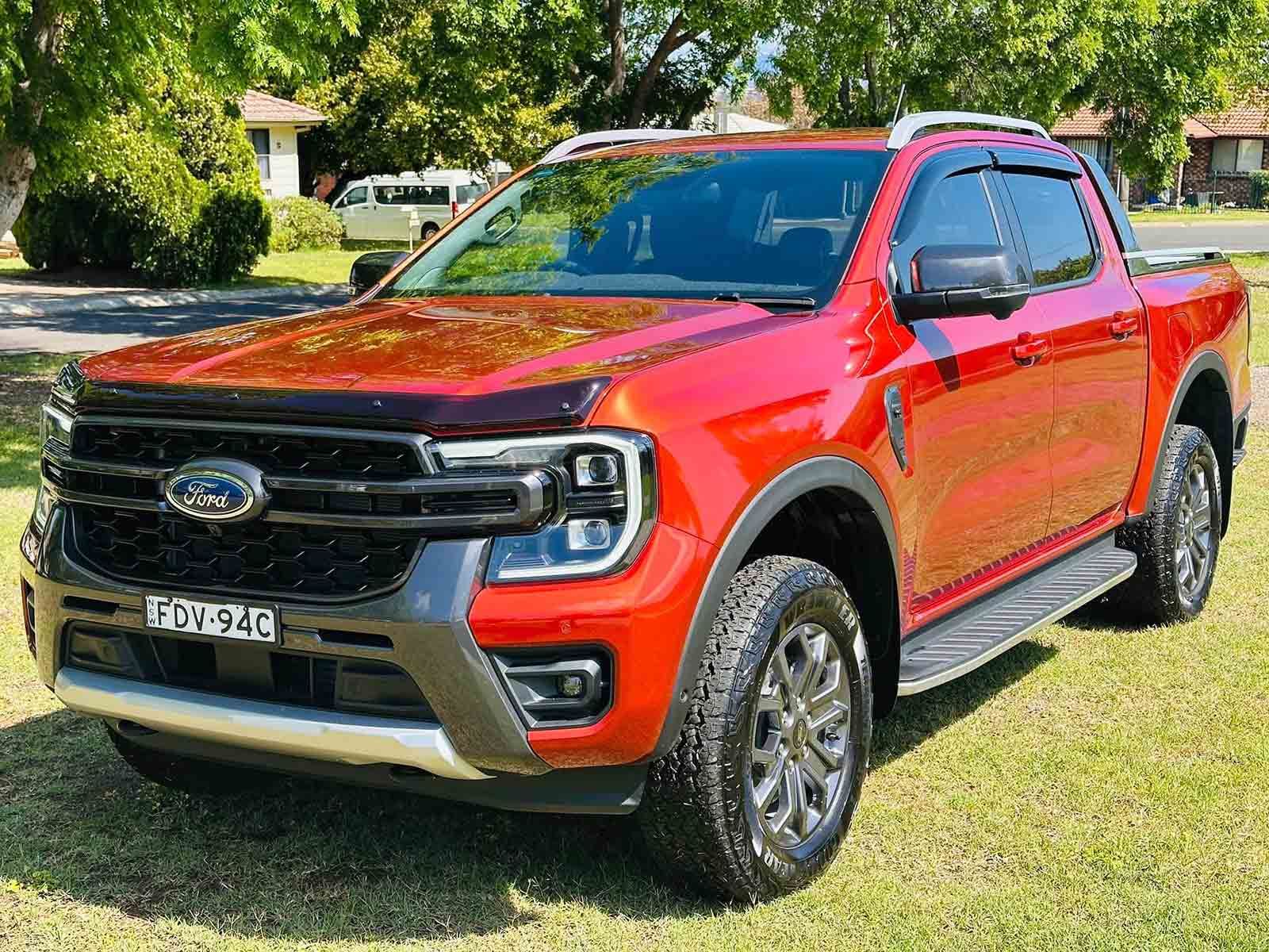 A Red Ford Ranger Is Parked In A Grassy Field — Brody’s Car Detailing In Tamworth, NSW