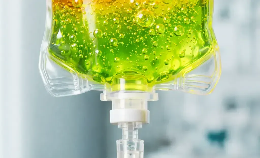 Close-up of a green liquid IV drip bag with visible bubbles and tubing