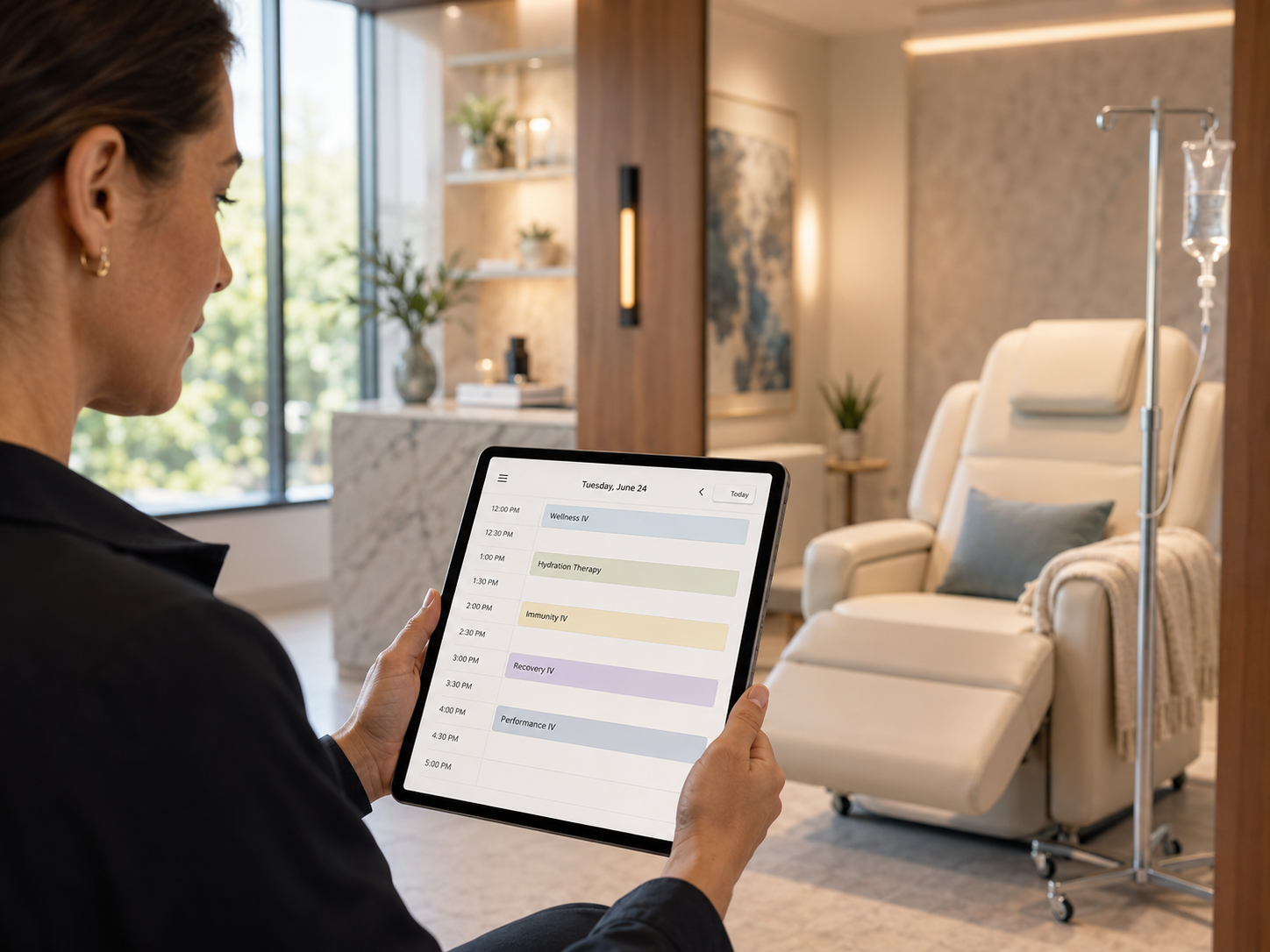 Person holding a tablet in a modern clinic waiting room with a white recliner and IV stand.