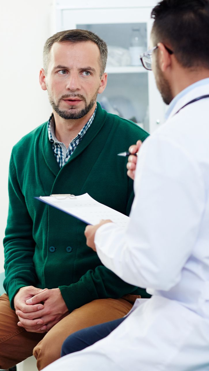 Patient listening to doctor during a medical consultation, with notes in hand.