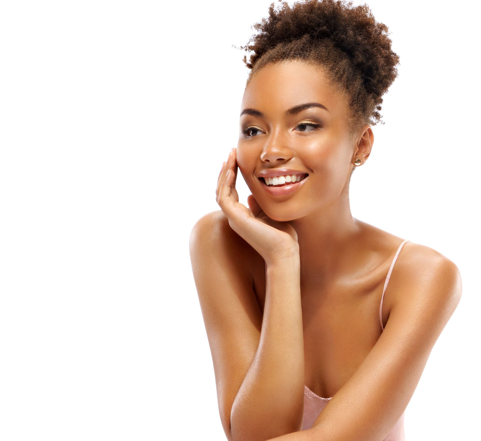 Smiling young Black woman with hand on face, wearing a light pink top and updo hairstyle, white background.
