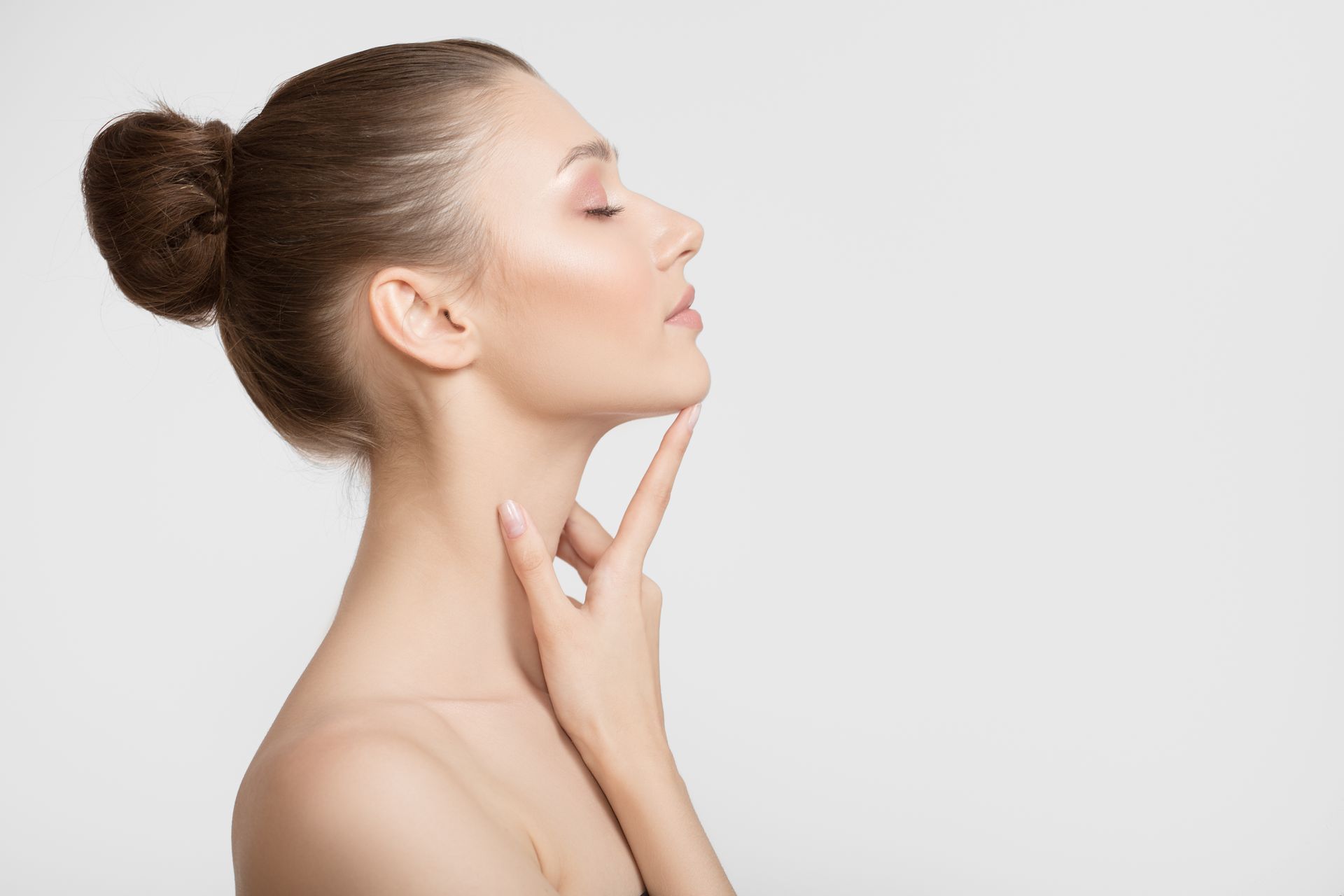 Woman with closed eyes, hand touching chin, profile view on a white background.