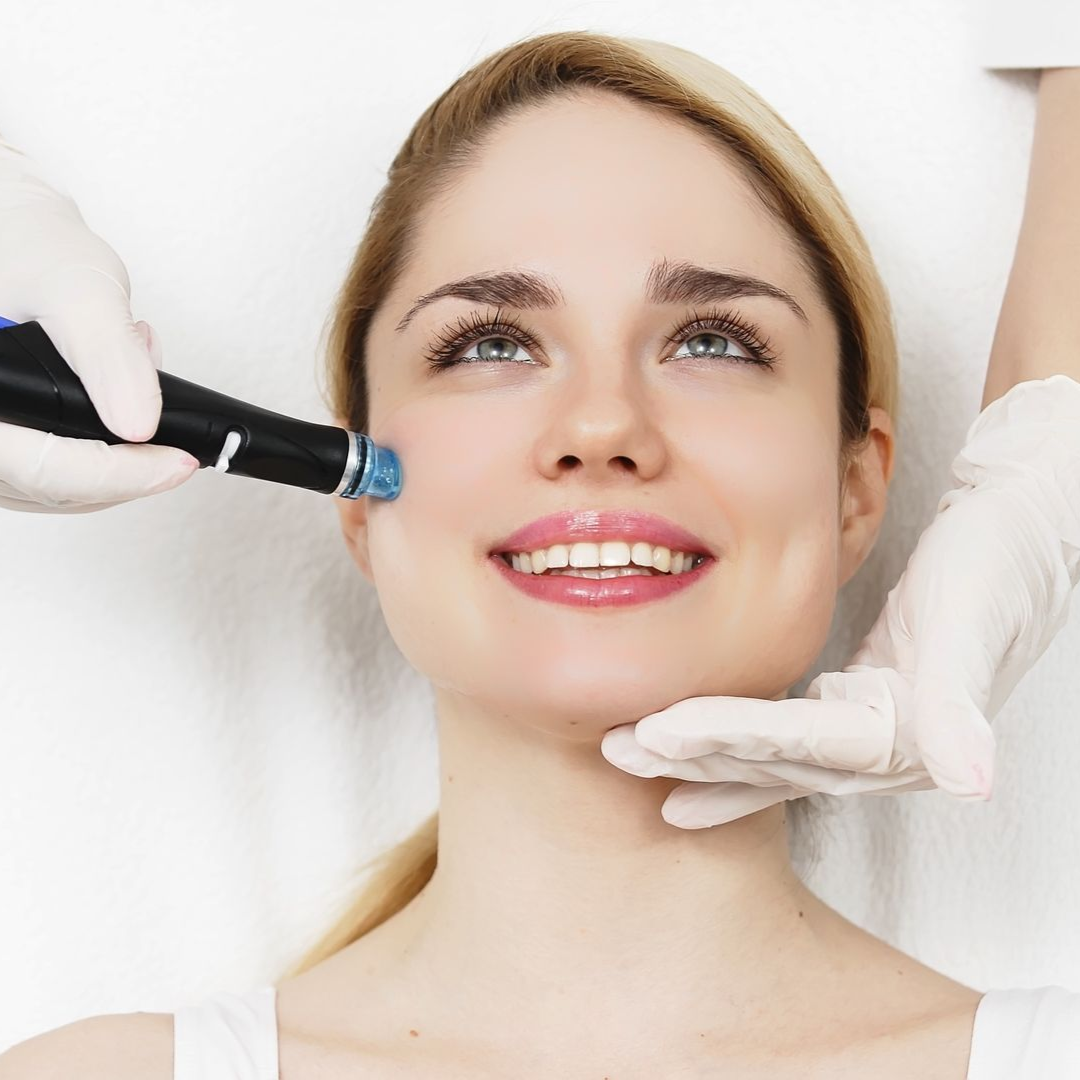 Woman receiving facial treatment with a handheld device, smiling, white-gloved hands.