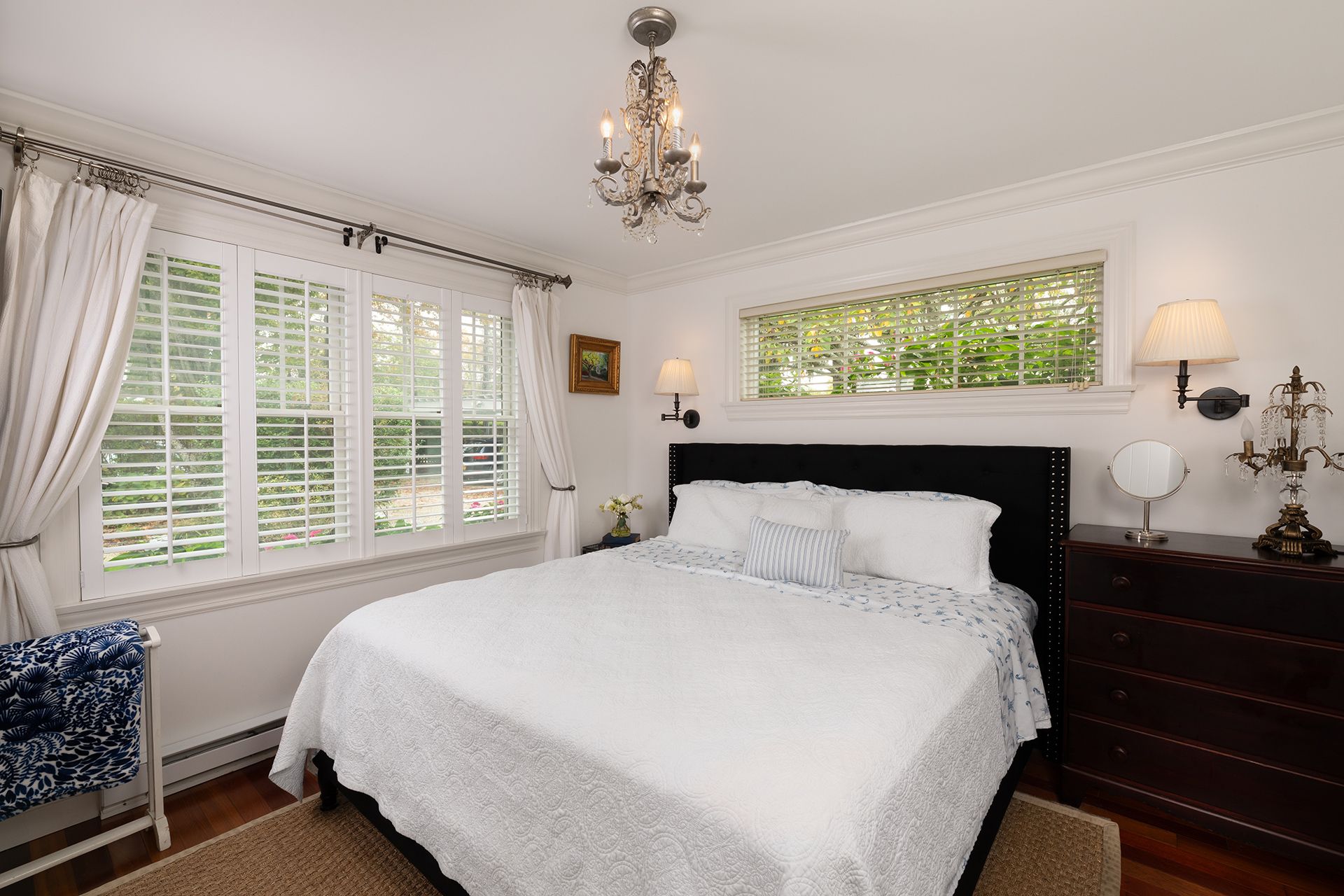 A bedroom with a bed , dresser , and window