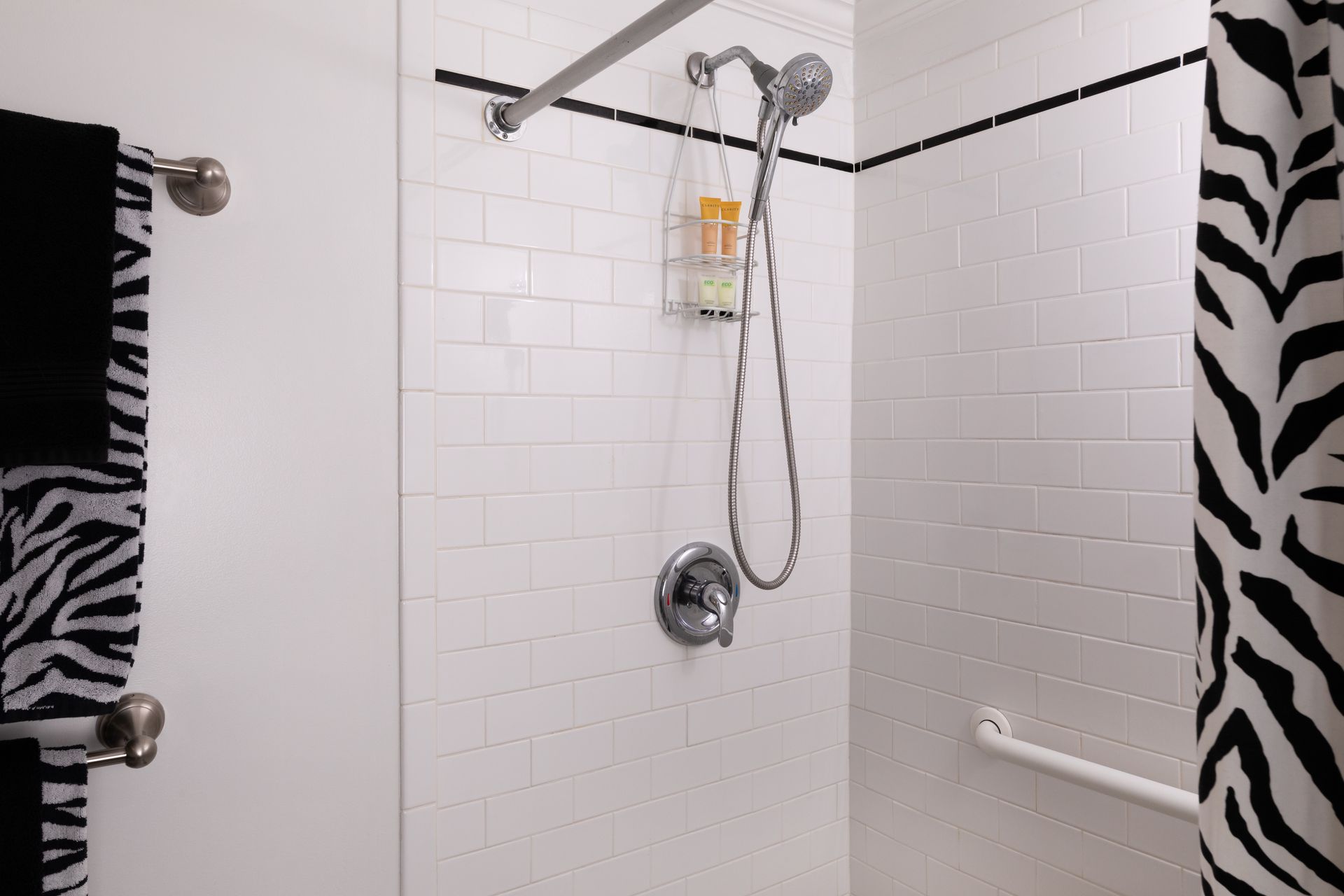 A black and white shower with a zebra print shower curtain.