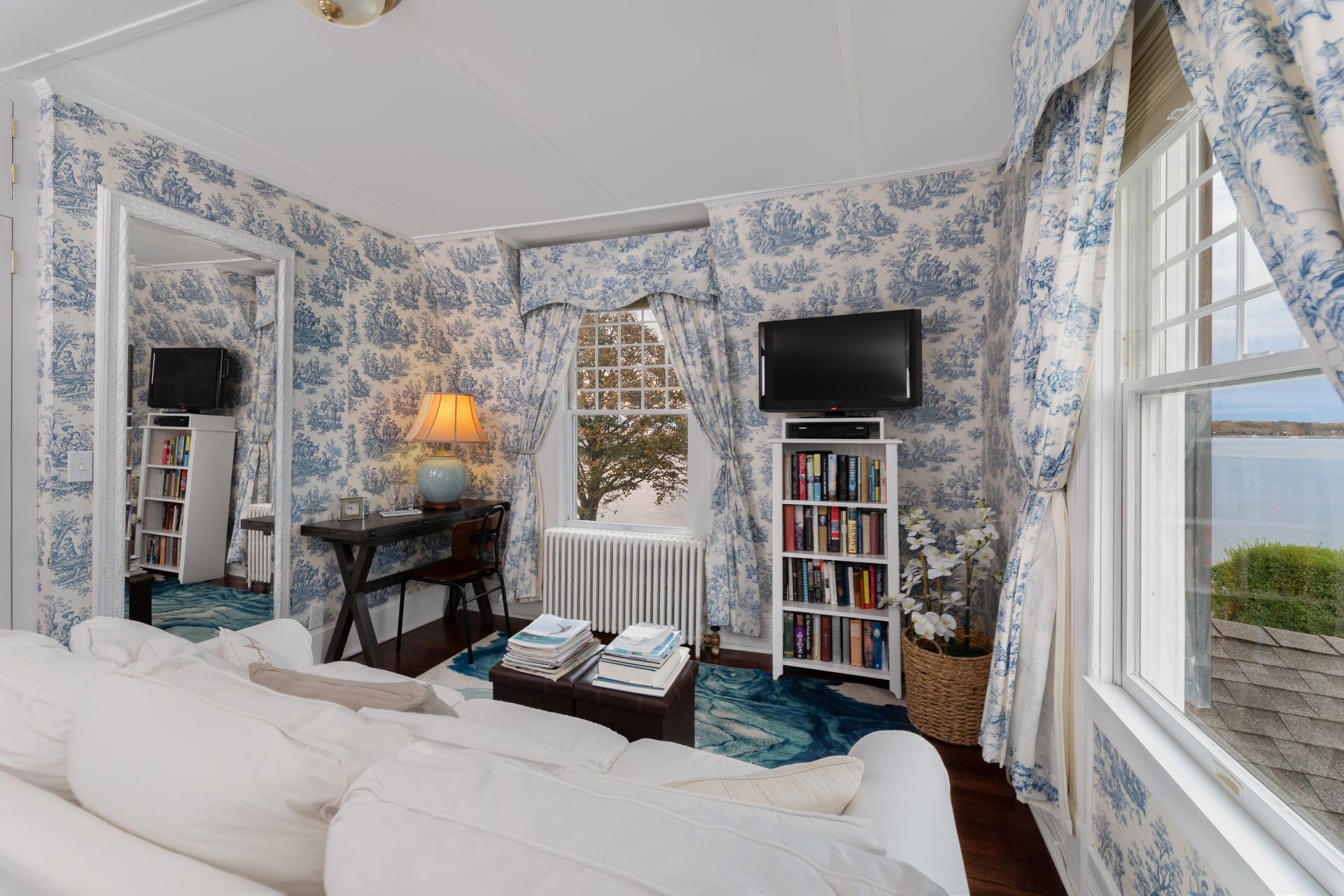 A living room with blue and white floral wallpaper and a couch.
