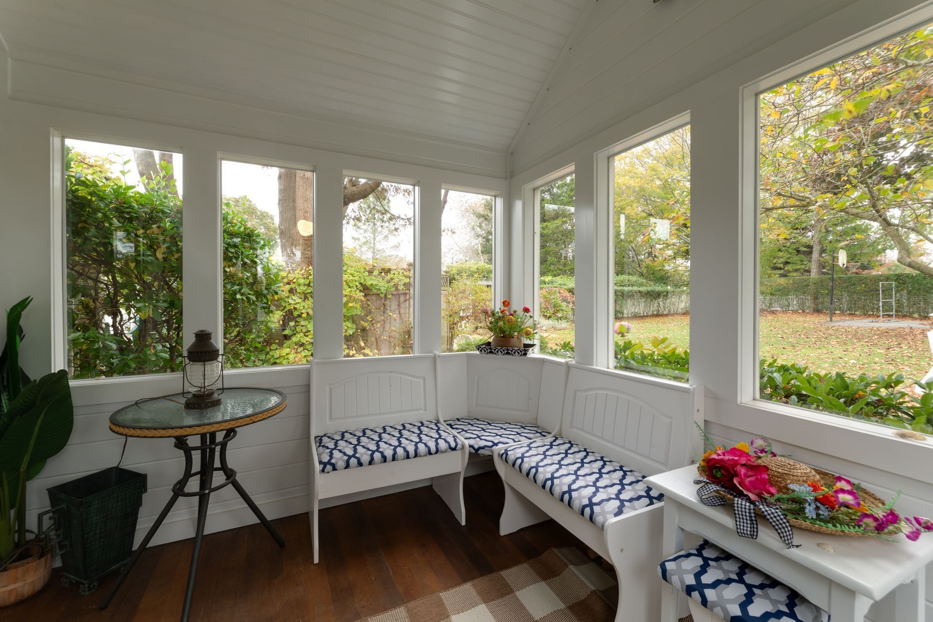 A sun room with a bench , table and windows.