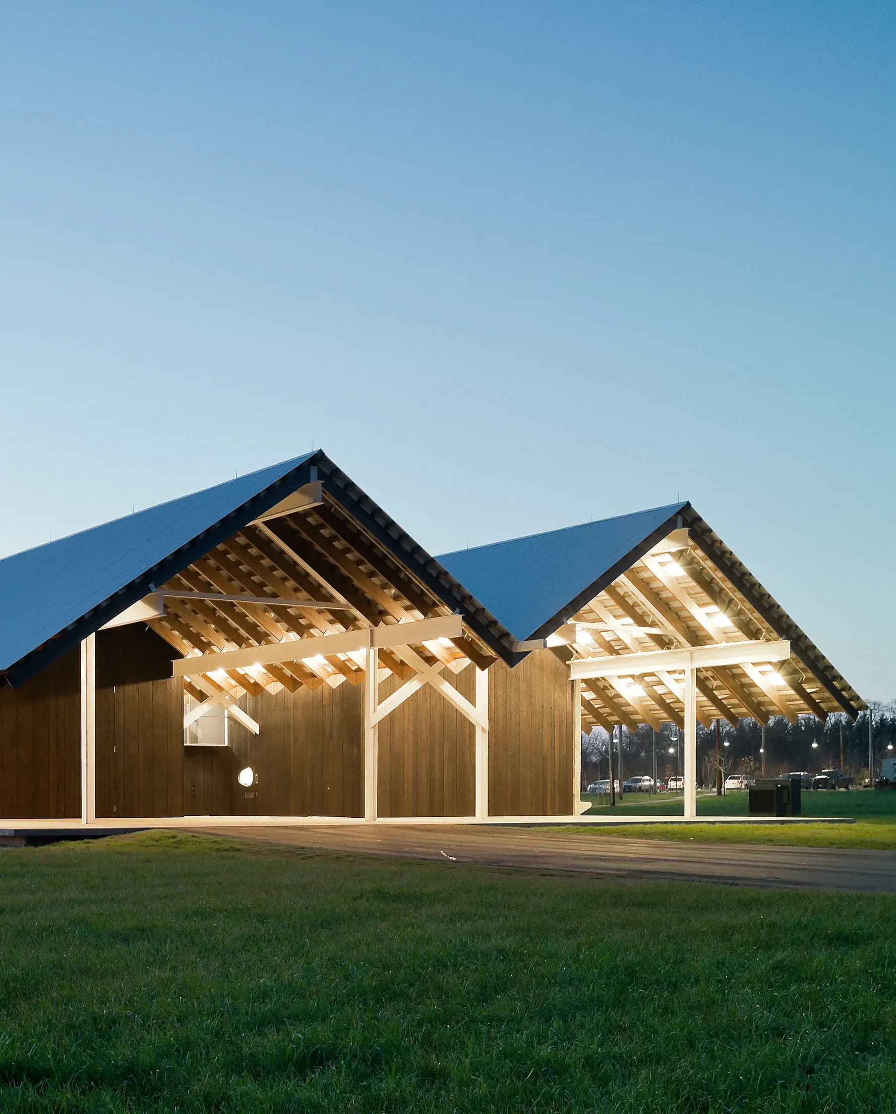 A large building with a blue roof is in the middle of a grassy field