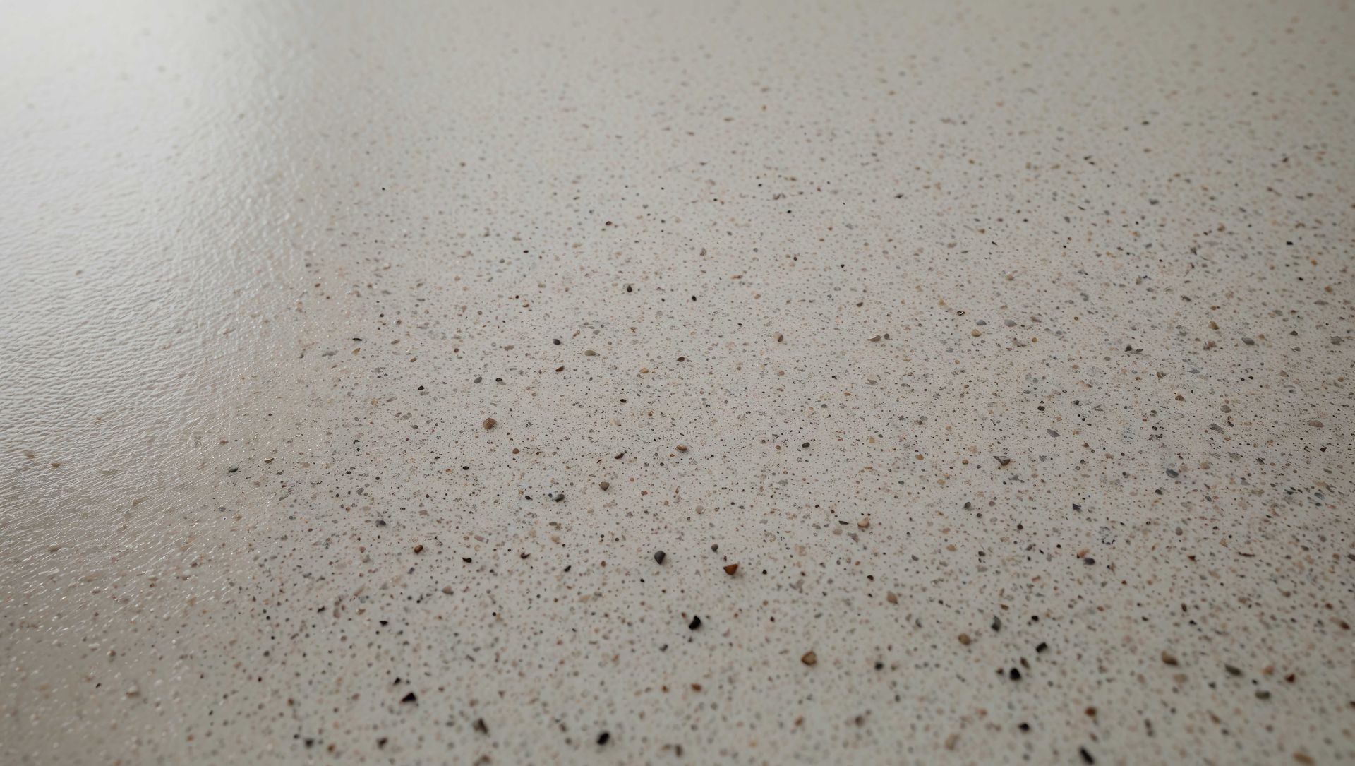 Light beige surface with scattered small dark specks across it.
