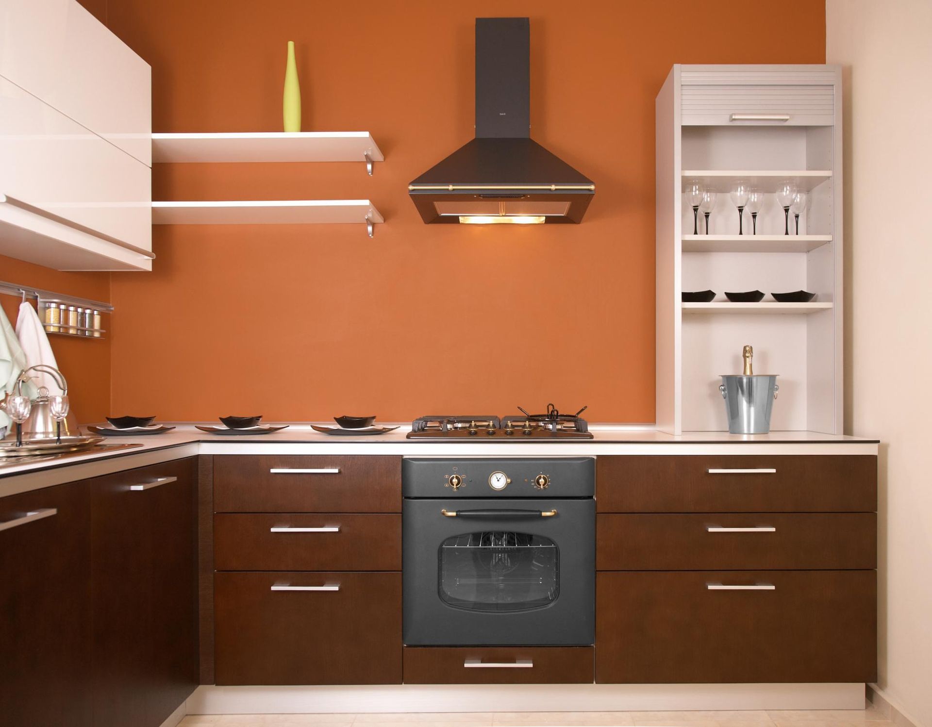 Modern kitchen with orange walls, dark wood cabinets, black range hood, and white shelves