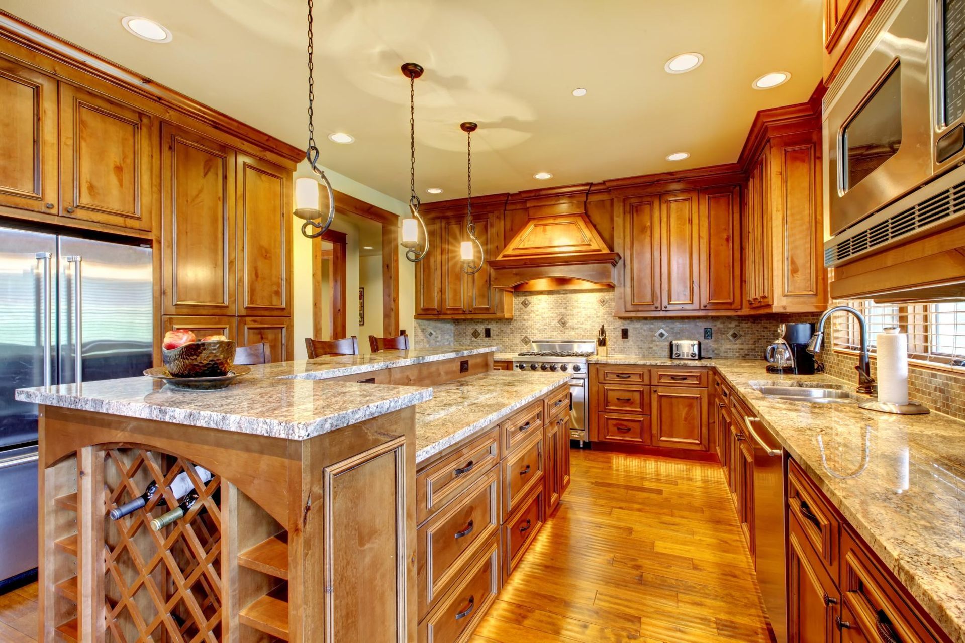 Spacious modern kitchen with wooden cabinets, granite counters, island, and stainless steel appliances