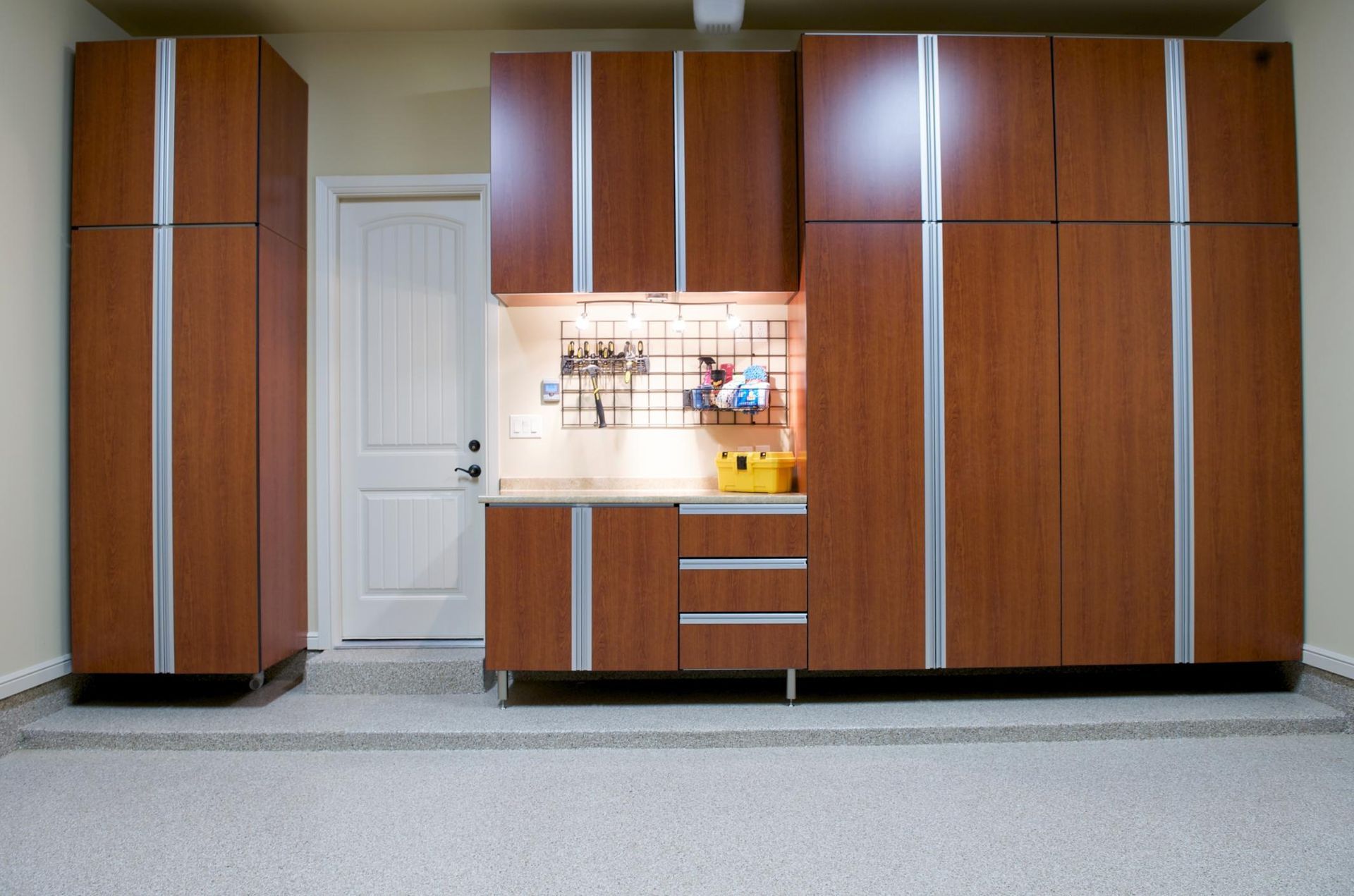 Wood-paneled kitchen cabinets with a sink, countertop, and white door in the center.