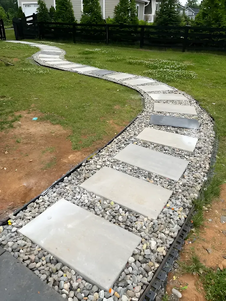 Curved stone garden path bordered by gravel across a grassy lawn
