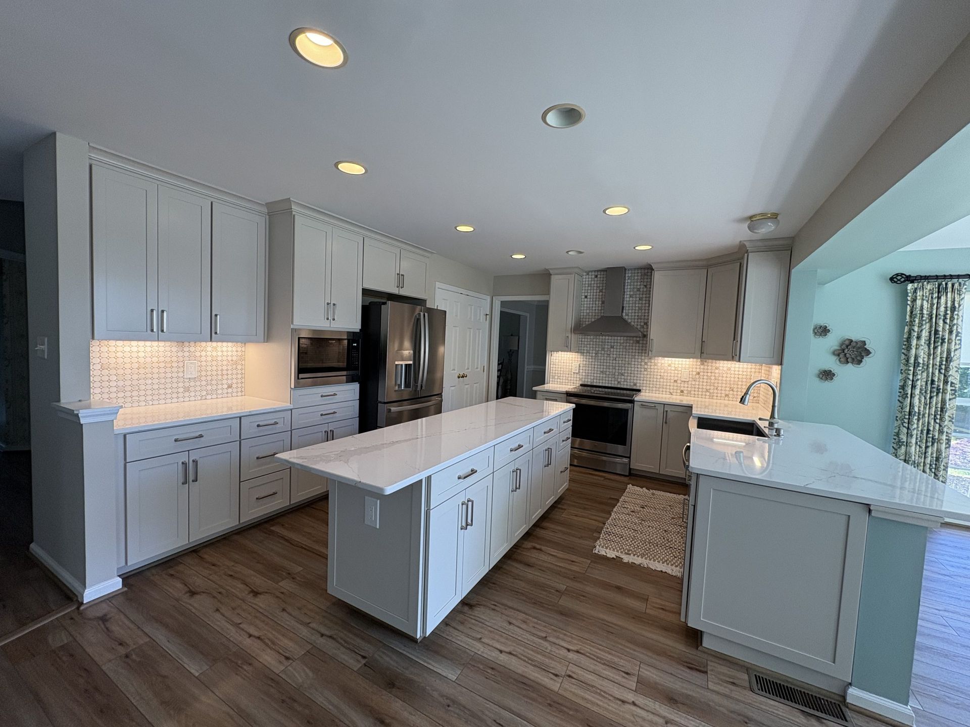 Bright modern kitchen with white cabinets, island, and wood floors