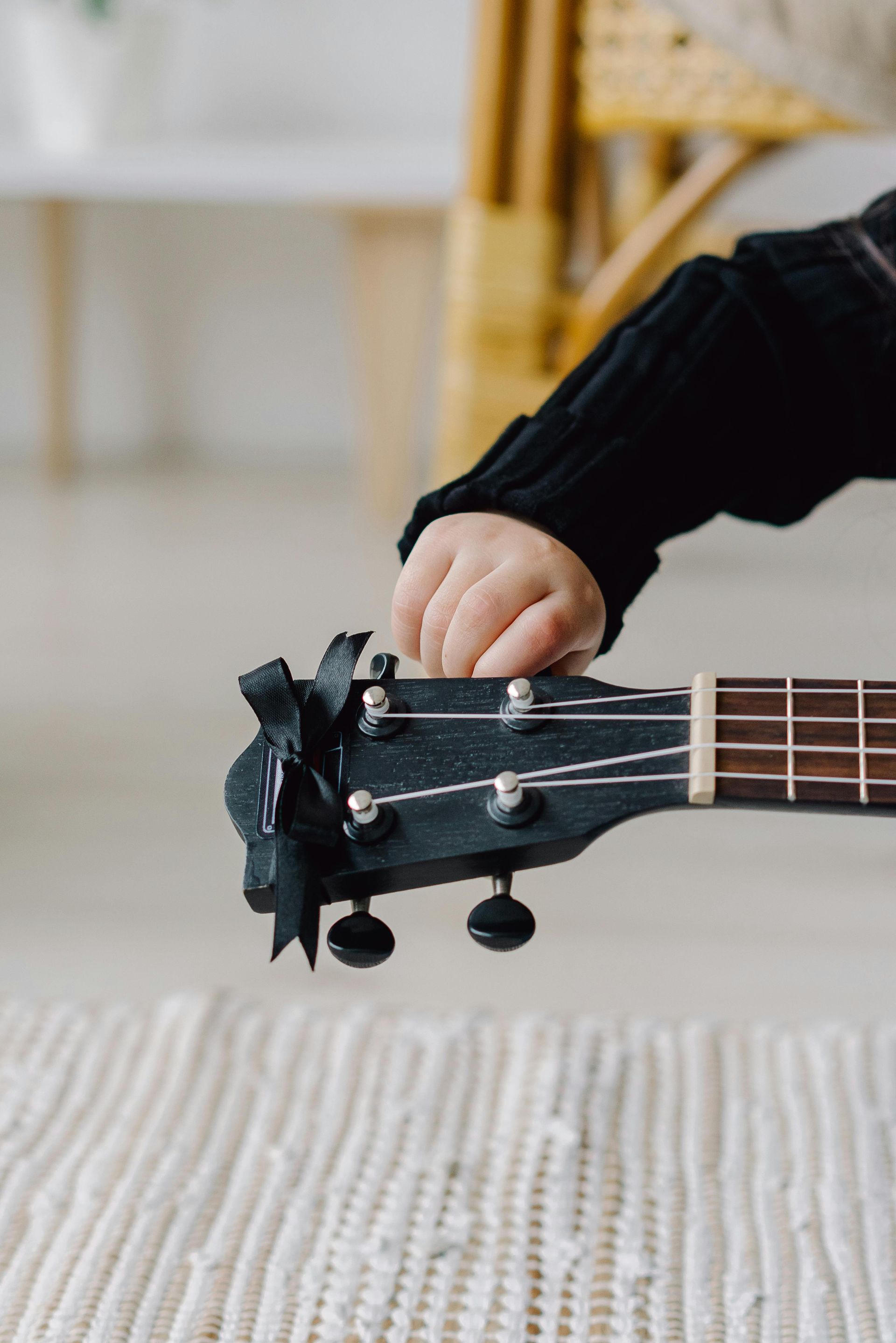 Kinderhand op de stemknop van een zwarte ukelele.