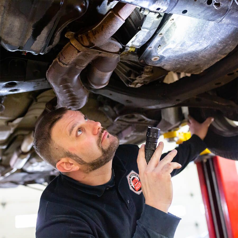 a man observing a car with torch | Ally Auto Service