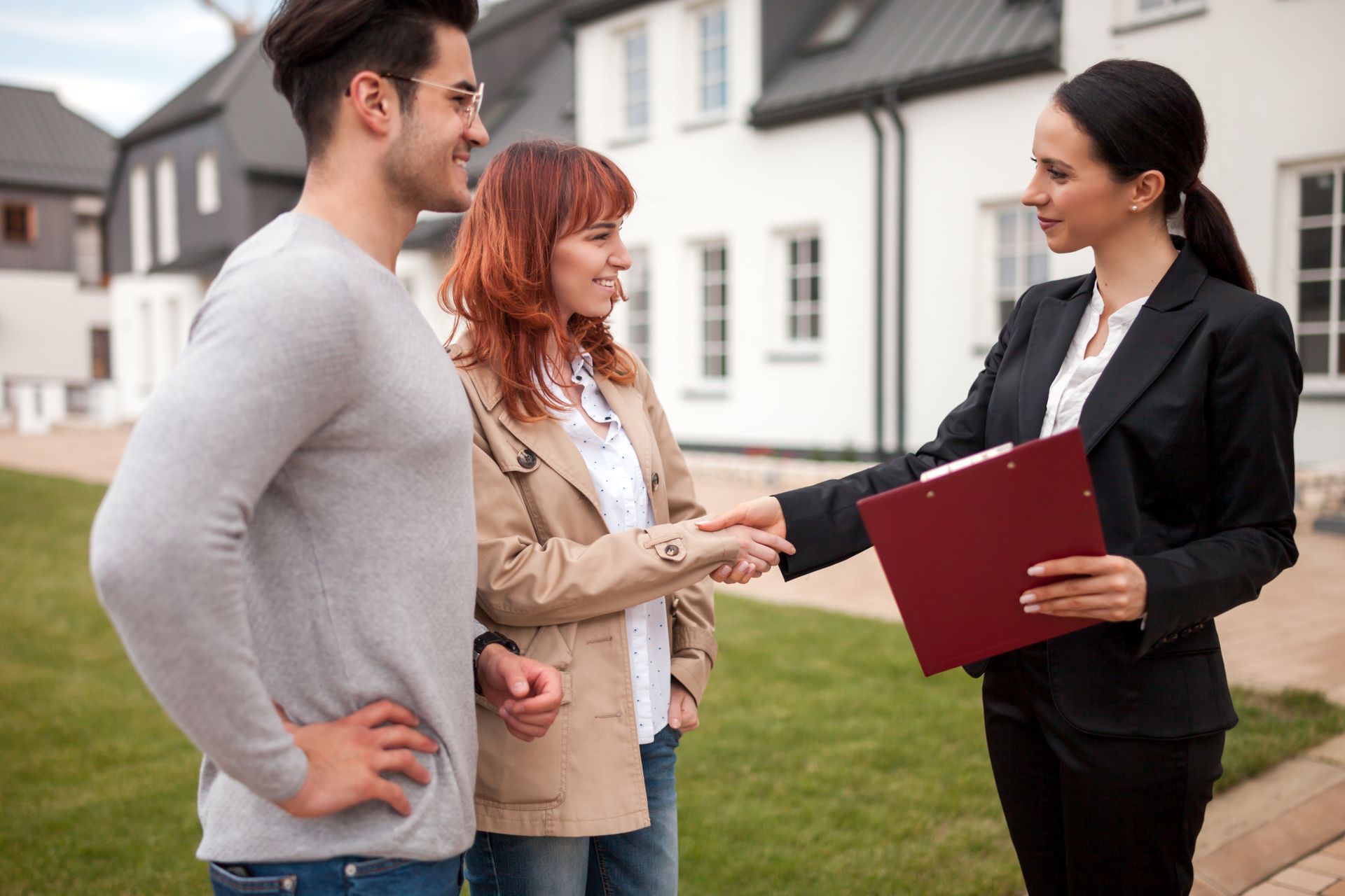 Real estate agent shaking hands with a couple in front of houses. Real estate agent shaking hands with a couple in front of houses.
