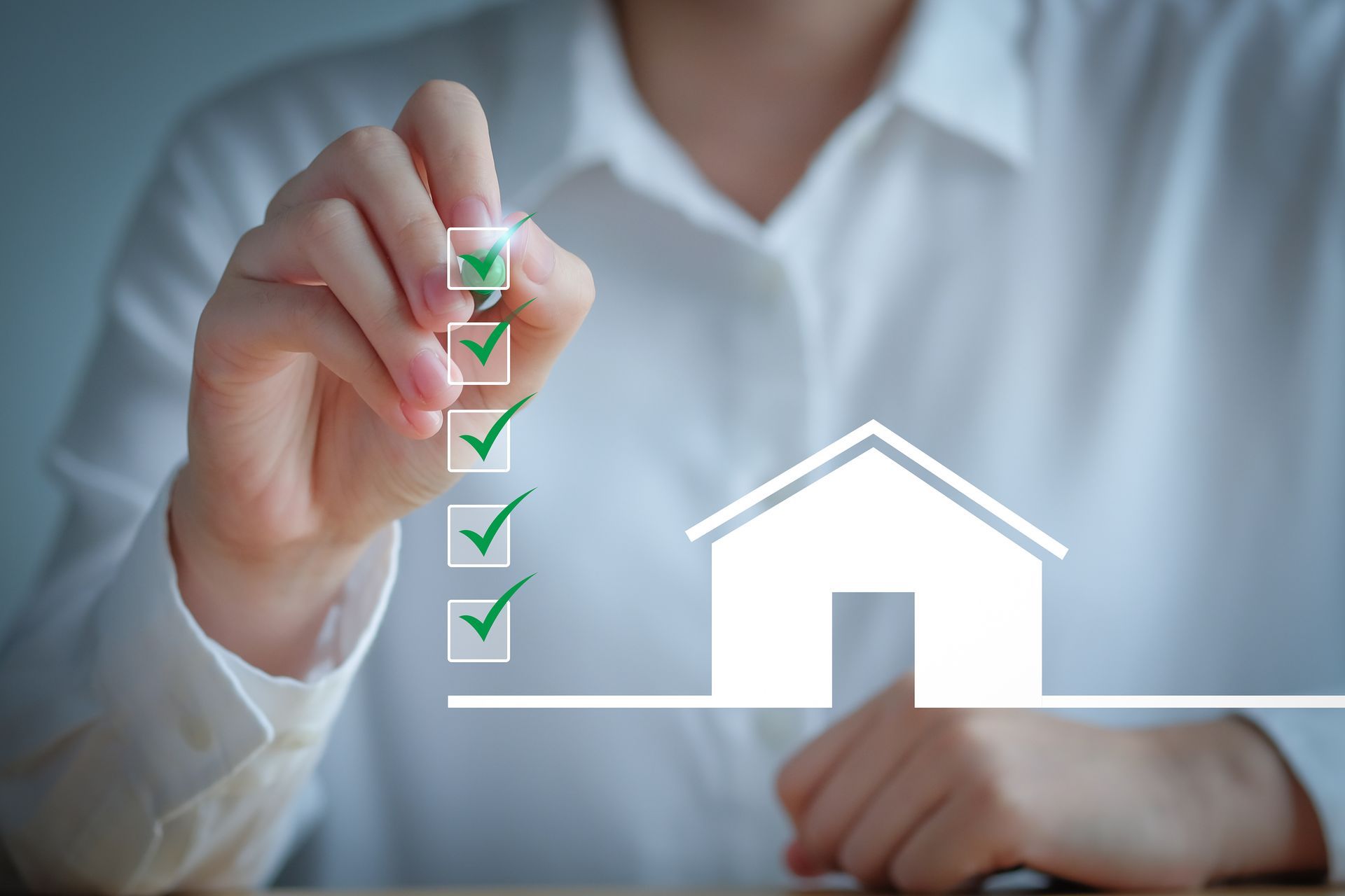 Hand with a pen checking a list of boxes with green checkmarks, next to a house outline. Hand with a pen checking a list of boxes with green checkmarks, next to a house outline.