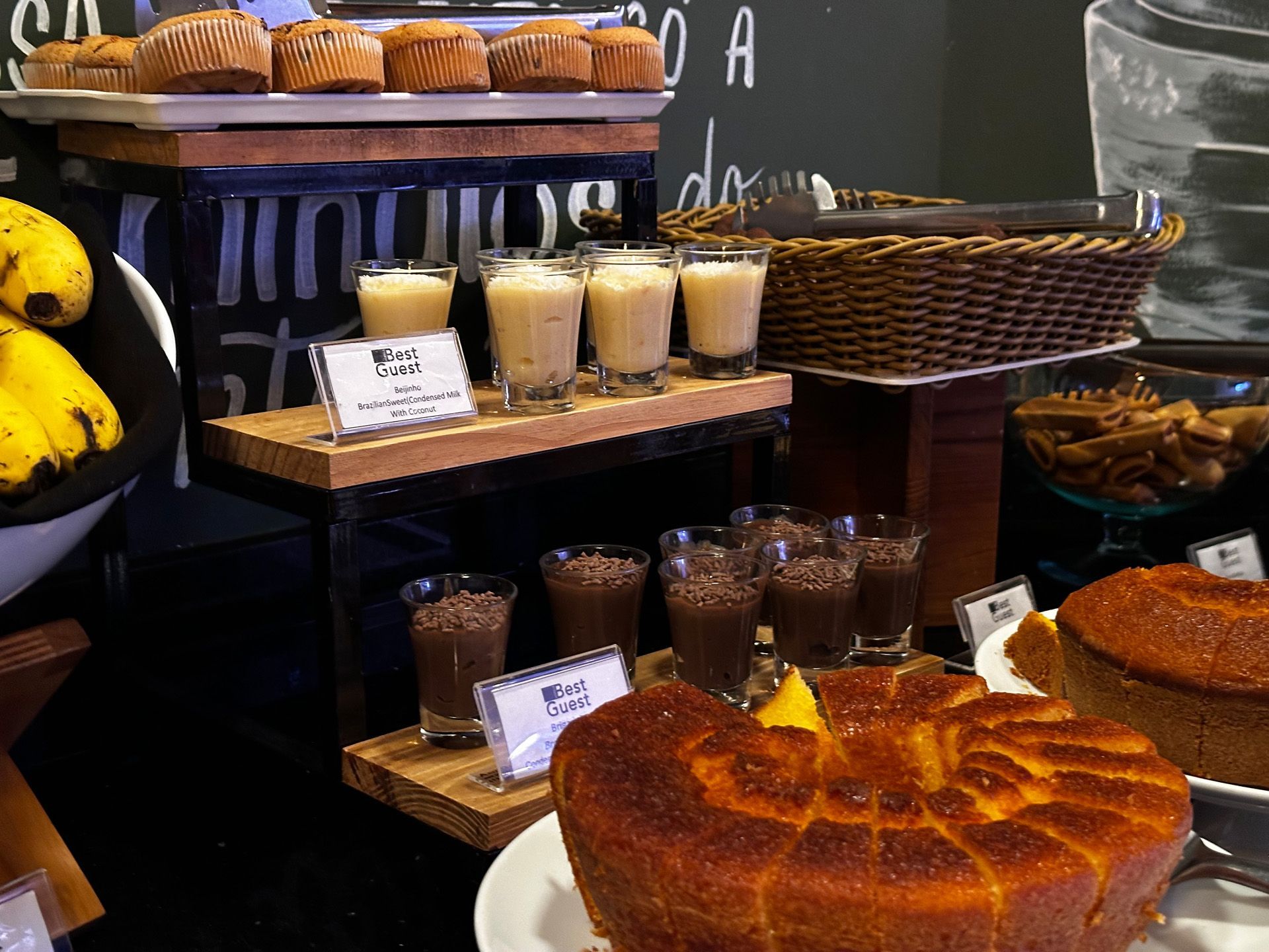 Buffet com doces, bebidas e bolos expostos em prateleiras de madeira de vários andares.