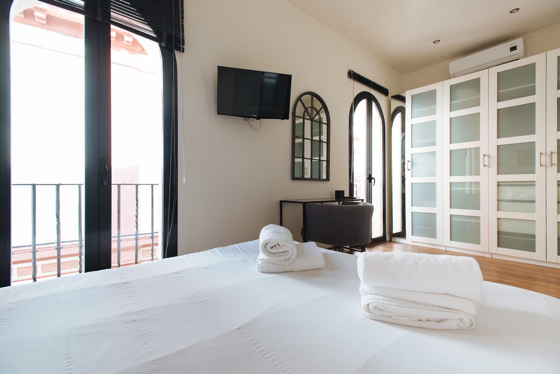 Bedroom with bed, closet, balcony, TV, and decorative mirror.