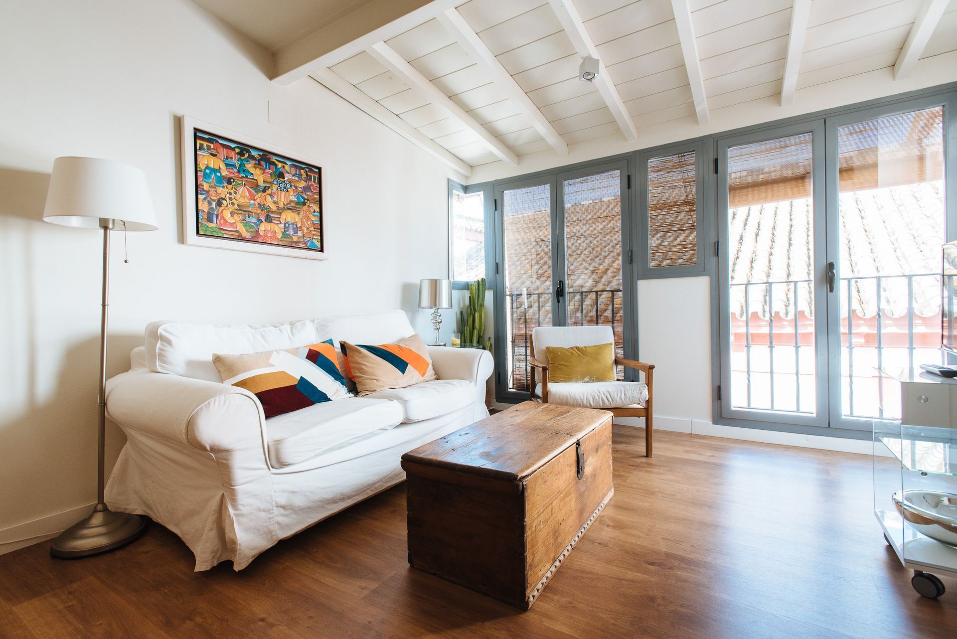 Living room with white sofa, wooden coffee table, and balcony doors.