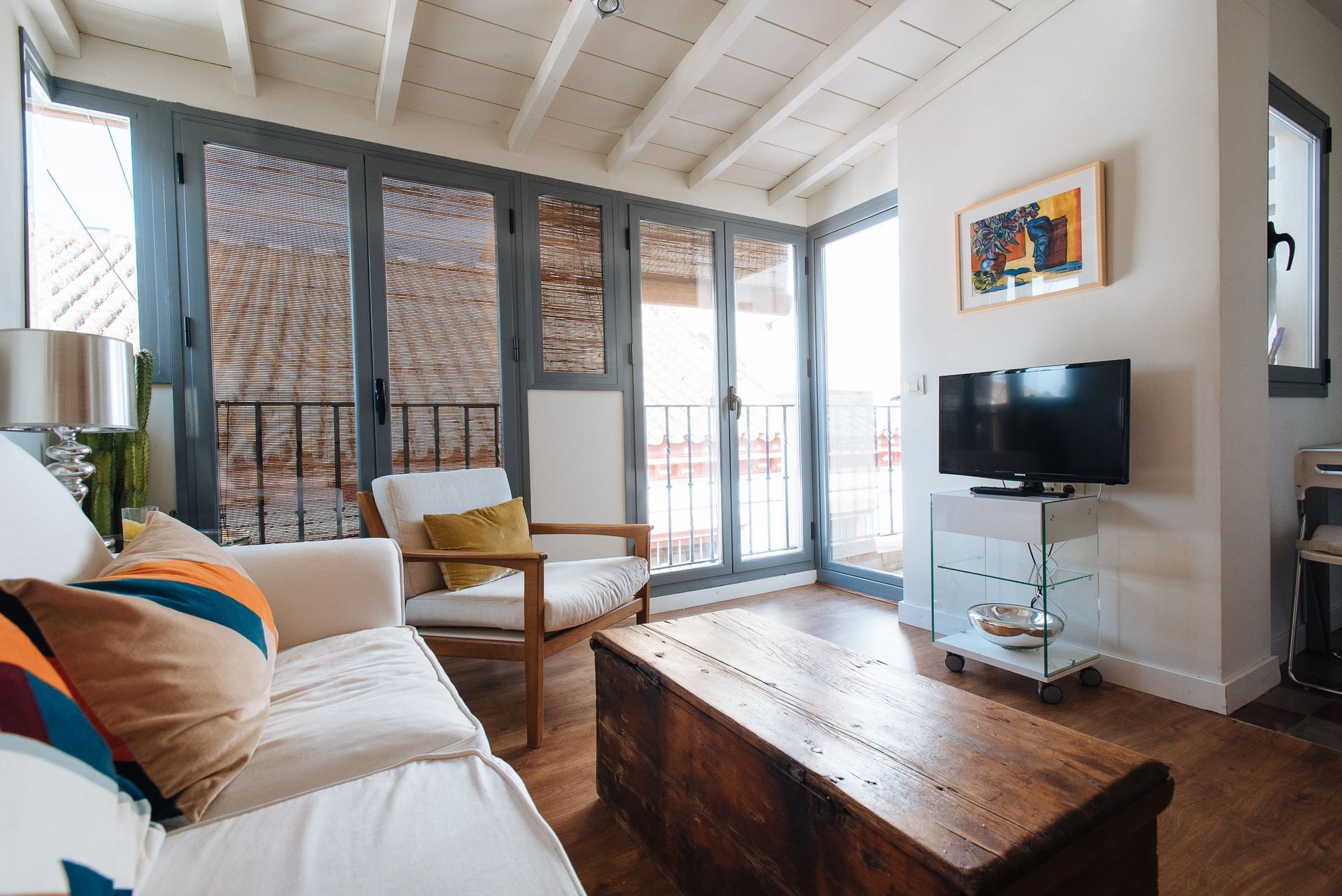 Living room with a white couch, wooden coffee table, and large window overlooking a balcony.