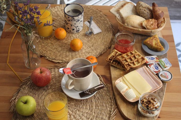 Breakfast spread with fruit, waffles, bread, and drinks on a wooden table.