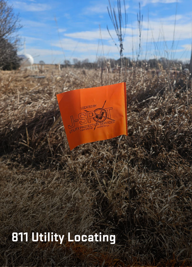 An orange utility locating flag marked OPTK Networks stands in a dirt field with other markers in the background.