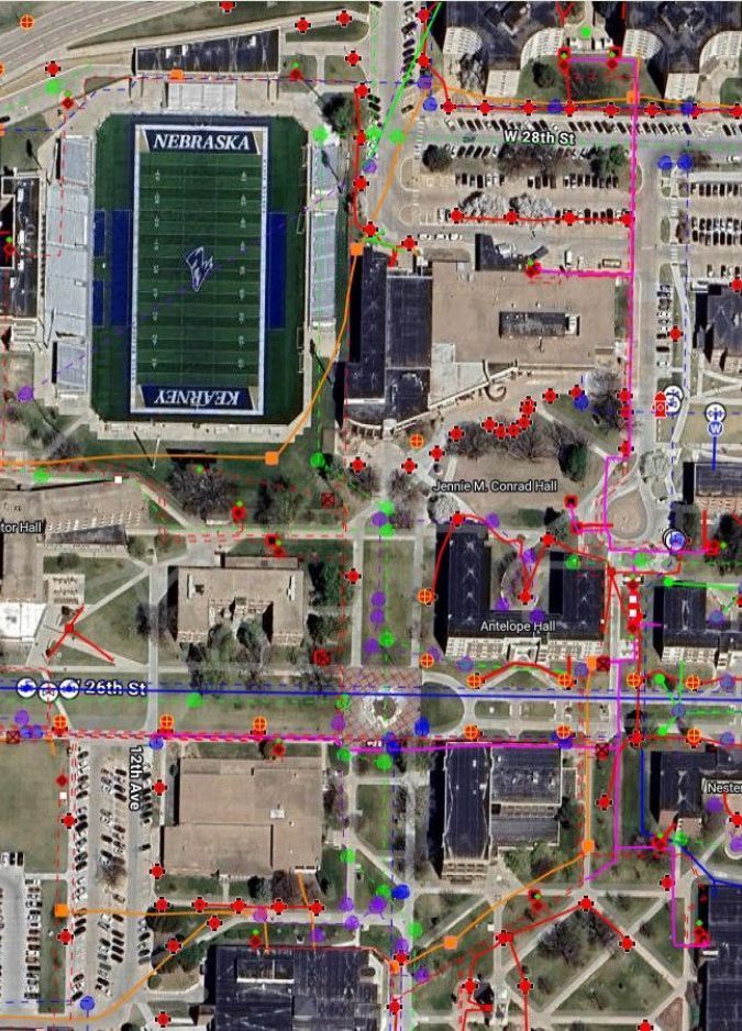 Satellite view of a road intersection overlaid with a network of colored lines and nodes for mapping or analysis.
