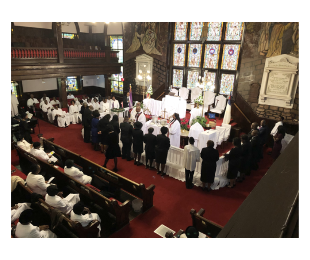 Interior of a church during a service, with people in attendance and a ceremony taking place at the altar.