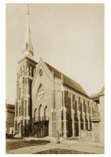 Sepia-toned photo of a church with a tall steeple, brick facade, and arched windows.