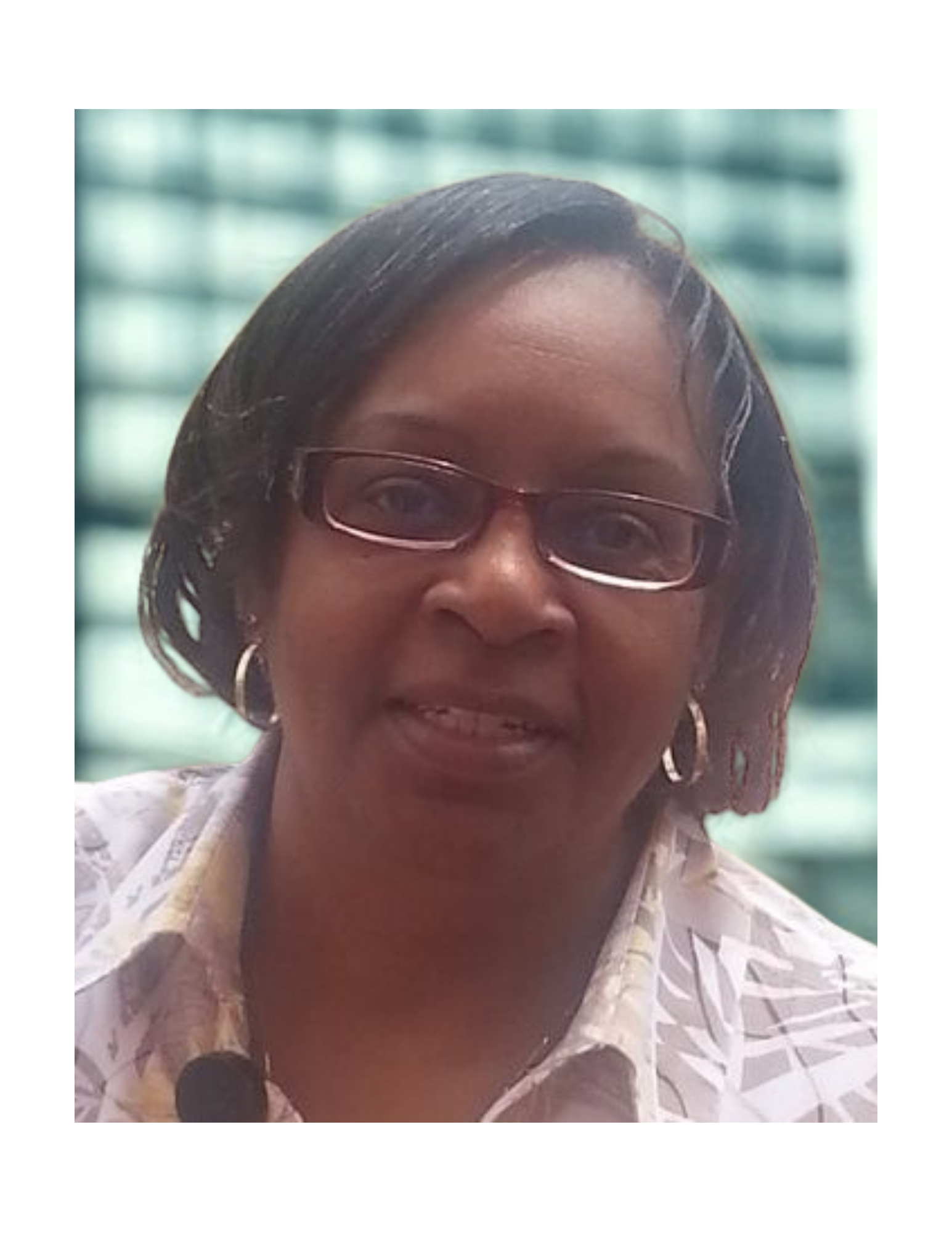 Woman wearing glasses smiles, outdoor background with light-colored, patterned shirt.