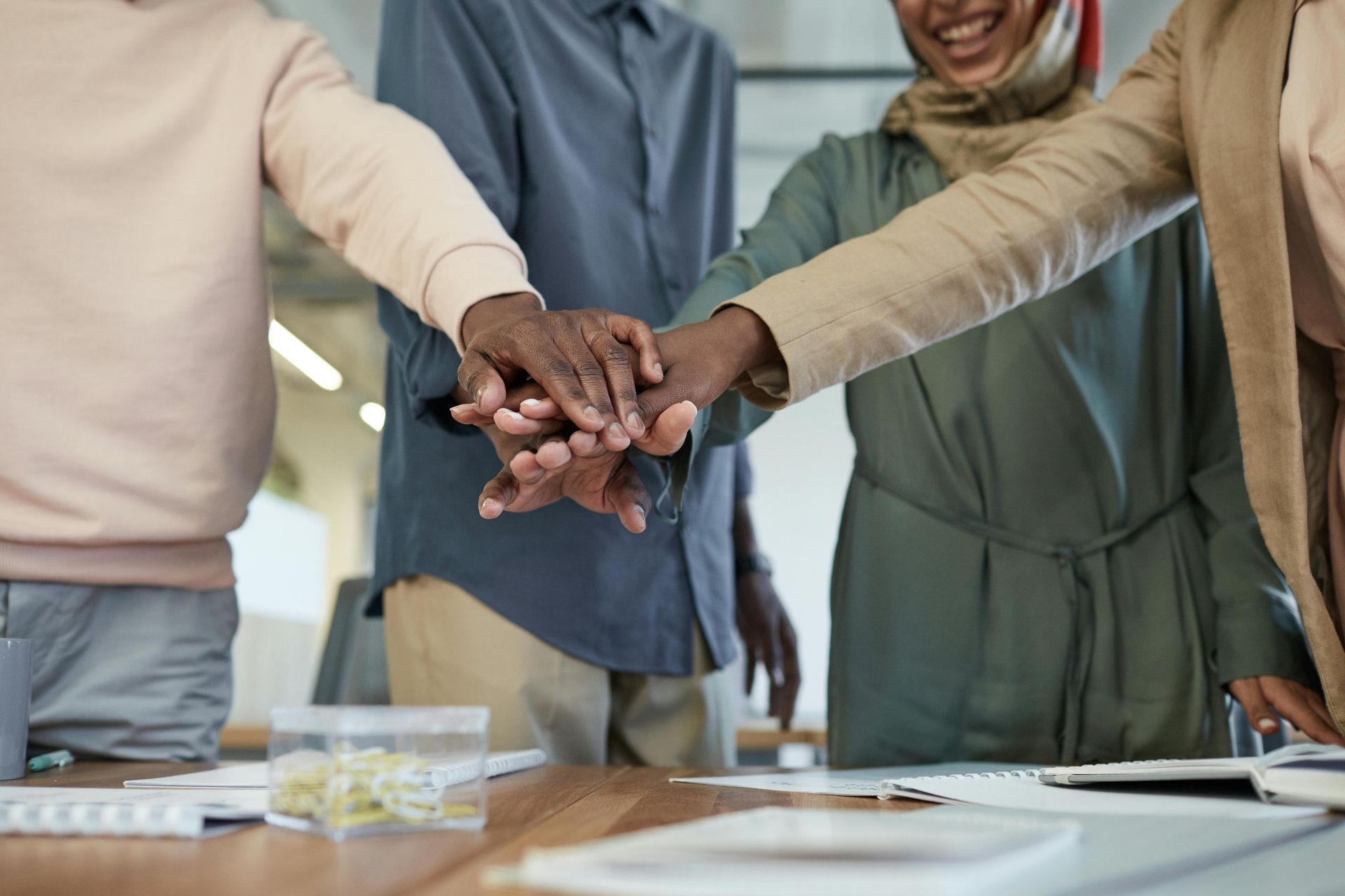 Hands stacked together on a table; team members' hands forming a pile.