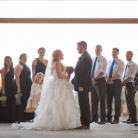Wedding couple standing at the altar with bridal party in a bright indoor venue