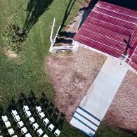 Overhead view of a red-roofed building, concrete path, and rows of white chairs on grass