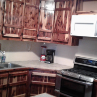 Small kitchen with dark wood cabinets, white countertops, stainless stove, and a coffee maker.