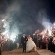 Bride and groom walk under sparklers at a nighttime outdoor wedding