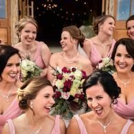 Smiling bridesmaids in pink dresses holding bouquets at a wedding reception